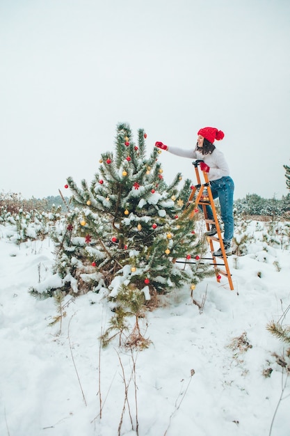 Mooie vrouw kerstboom buitenshuis versieren