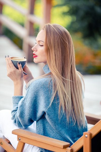 mooie vrouw koffie drinken in de herfst park onder val gebladerte