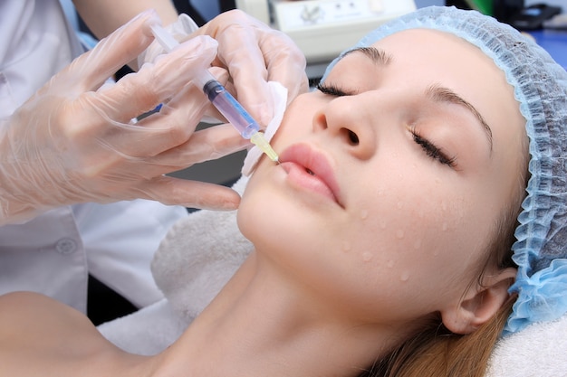 Mooie vrouw krijgt een injectie in haar lippen.