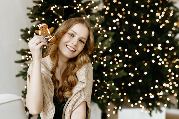 Mooie vrouw lacht thuis tegen de achtergrond van een kerstboom