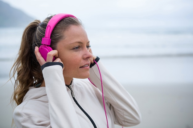 Mooie vrouw luisteren muziek op koptelefoon op strand