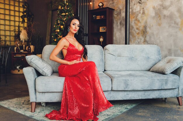 Mooie vrouw meisje in de studio van het nieuwe jaar poseren, foto Nieuwjaar fotosessie. Mooi meisje in een luxe jurk met slanke benen. Kerstmis, winter, geluk concept.