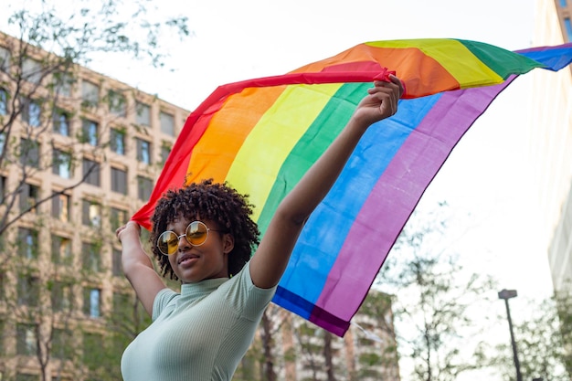 Mooie vrouw met afrohaar die de LGBTI-trotsvlag zwaaien