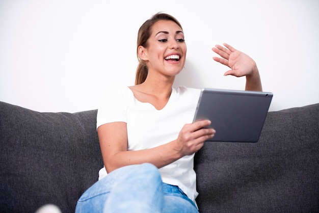 Mooie vrouw met behulp van haar tablet op een bank in een woonkamer