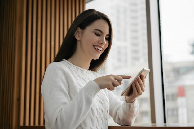 Mooie vrouw met behulp van mobiele telefoon, online winkelen, eten bestellen, thuis blijven