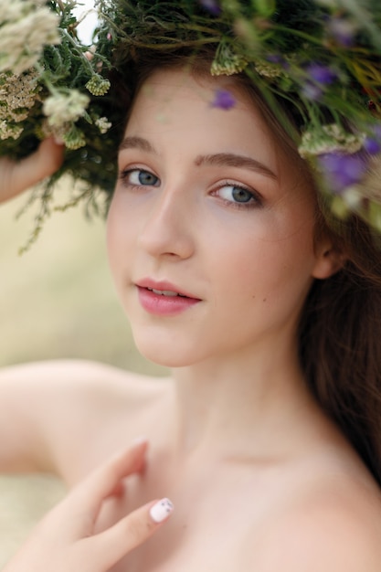Mooie vrouw met bloemkroon op haar hoofd. Schoonheidsmeisje met bloemenkapsel. Meisje in een zomerbos. Mode foto
