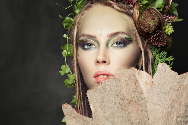 Mooie vrouw met creatieve make-up groene bladeren en boom schors Halloween personage