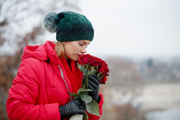 Mooie vrouw met een boeket rode rozen in haar handen