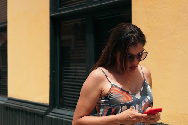 Mooie vrouw met een bril die door de straat loopt met haar mobiele telefoon