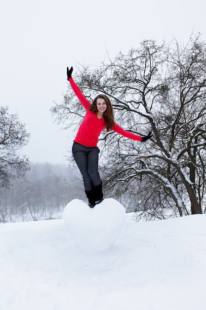 Mooie vrouw met een enorm hart gemaakt van sneeuw