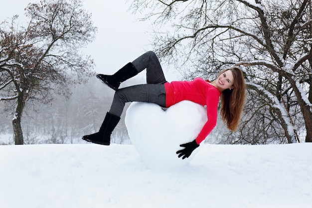 Mooie vrouw met een enorm hart gemaakt van sneeuw