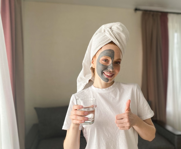 Foto mooie vrouw met een handdoek op haar hoofd en een kleimasker