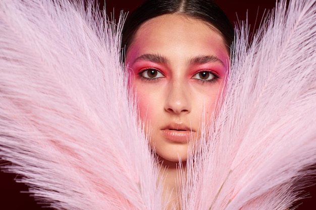 Mooie vrouw met een kam lichte make-up poseren pluizige veren geïsoleerde achtergrond ongewijzigd