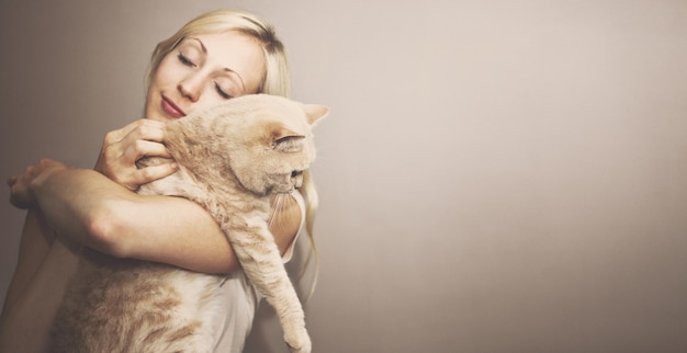 Mooie vrouw met een kat op een beige achtergrond.