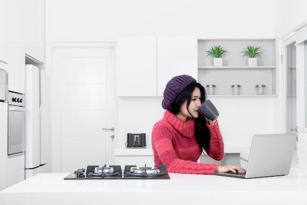 Mooie vrouw met een laptop in de keuken.