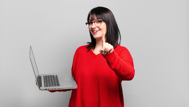 Mooie vrouw met een maatje meer die trots en zelfverzekerd glimlacht en nummer één triomfantelijk poseert en zich een leider voelt