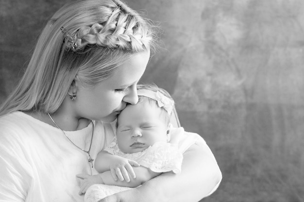 Mooie vrouw met een pasgeboren babymeisje in haar armen Gelukkige moeder kuste haar uitglijdende pasgeboren baby Gelukkig familieconcept Close-up foto