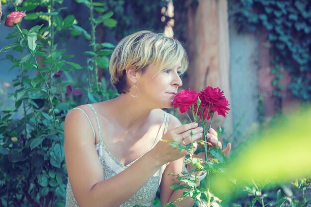 Foto mooie vrouw met een rode bloem in de achtertuin.