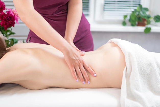 Mooie vrouw met een wellness-rugmassage in de spa salon Masseurs handen doen rugmassage in het spacentrum