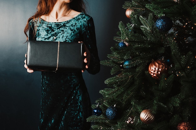 Mooie vrouw met geschenkdoos in de buurt van de kerstboom