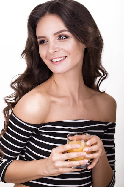 Mooie vrouw met gezonde huid haarkrullen en sinaasappelsap poseren in studio Beauty face