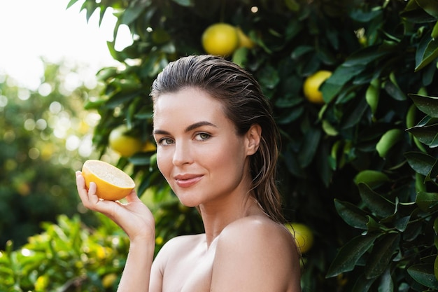 Mooie vrouw met gladde huid met een citroenfruit in haar handen