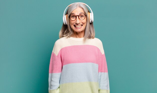 Mooie vrouw met grijs haar die muziek luistert met haar koptelefoon