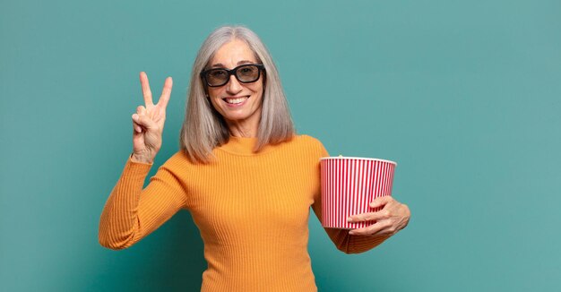 Mooie vrouw met grijs haar en een emmer met popcorn