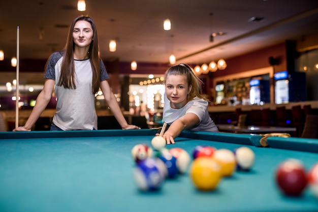 Mooie vrouw met haar vriend biljart spelen in de pub