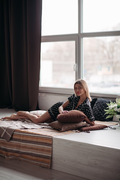 Mooie vrouw met kort blond haar die een kussen vasthoudt en glimlacht