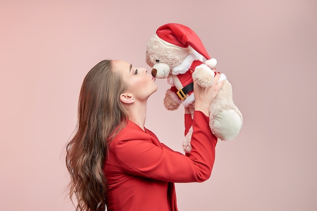 Mooie vrouw met lang golvend haar kust een speelgoedbeer in de afbeelding van de kerstman.