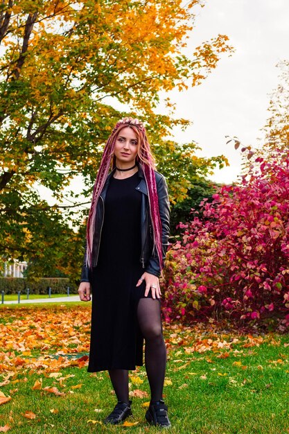 Mooie vrouw met lang haar in zwarte kleren in het de herfstpark Portret van volledige lengte