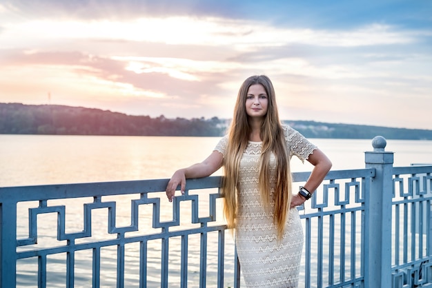 Mooie vrouw met lang haar poseren tegen zonsondergang