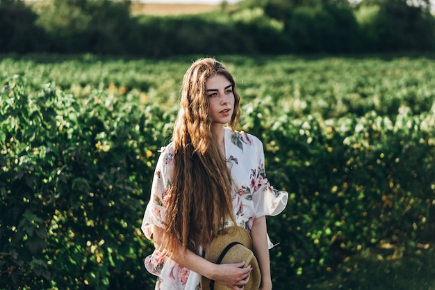 Mooie vrouw met lang krullend haar en sproeten gezicht op bes veld. vrouw in een lichte jurk wandelingen in de zonnige zomerdag