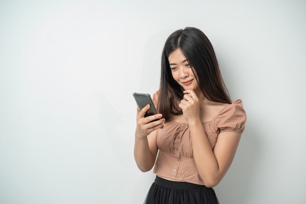 Mooie vrouw met lange haarglimlach en status gebruikend slimme telefoon