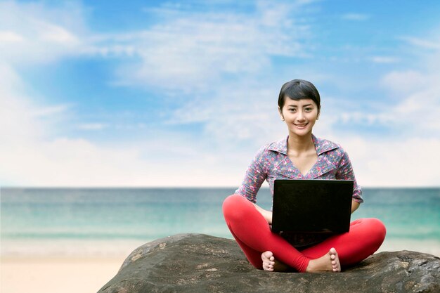 Mooie vrouw met laptop op het strand.