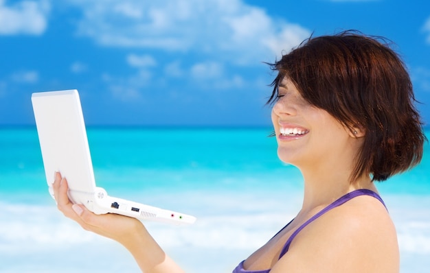 mooie vrouw met laptop op het strand