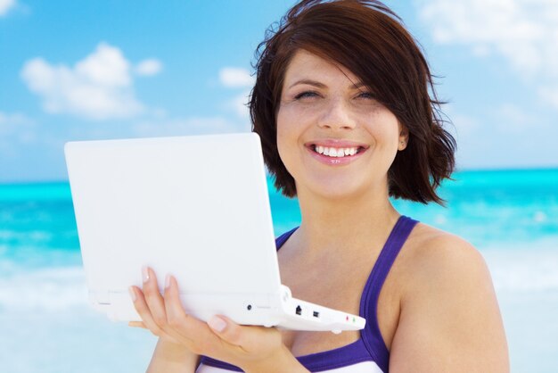 mooie vrouw met laptop op het strand