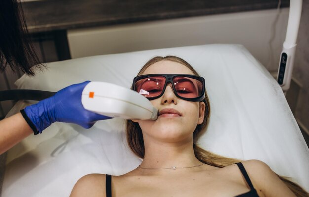 Mooie vrouw met laserontharing en laserepilatie op het gebied van de lippen op haar gezicht in de cosmetologiesalon