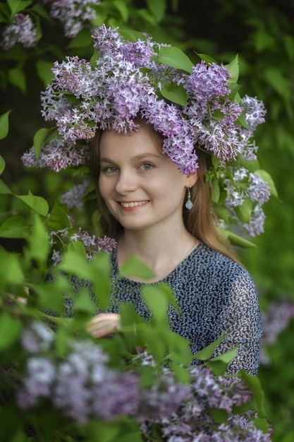 Mooie vrouw met lila bloemenkrans Meisje in een krans van lila in de lente Lila krans