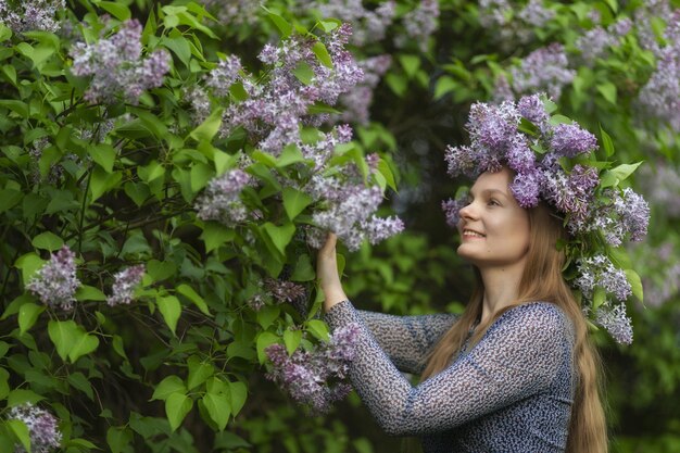 Mooie vrouw met lila bloemenkrans Meisje in een krans van lila in de lente Lila krans