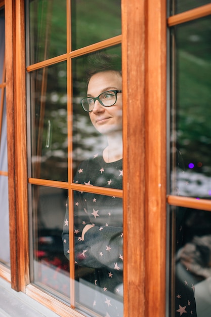 Mooie vrouw met mooi gezicht kijkt door het weerspiegelde raam