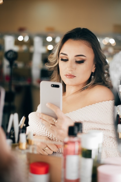 Mooie vrouw met mooie make-up neemt een selfie in de spiegel in de schoonheid