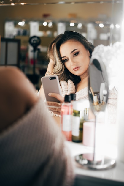 Mooie vrouw met mooie make-up neemt een selfie in de spiegel in de schoonheid