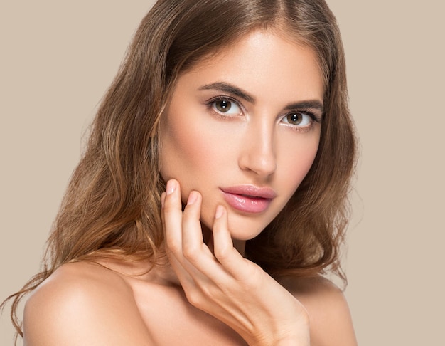 Mooie vrouw met natuurlijke make-up casual dagelijkse cosmetica die haar gezicht aanraakt. kleur achtergrond bruin