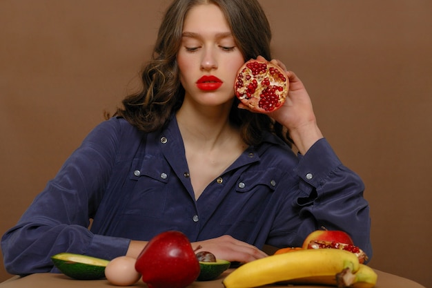 Mooie vrouw met rode lippenstift poseren met fruit