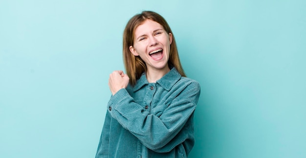 Mooie vrouw met rood haar die zich gelukkig, positief en succesvol gemotiveerd voelt wanneer ze voor een uitdaging staat of goede resultaten viert