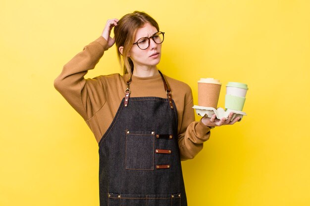 Mooie vrouw met rood hoofd die gelukkig glimlacht en dagdroomt of twijfelt om koffieconcept mee te nemen