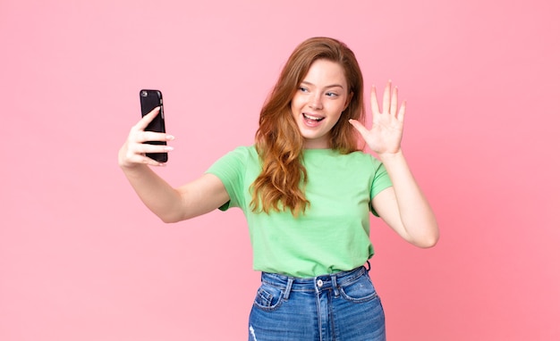 Mooie vrouw met rood hoofd die haar smartphone gebruikt