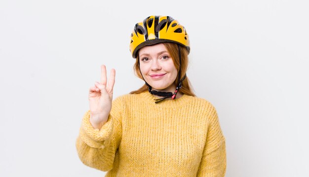 Mooie vrouw met rood hoofd lacht en ziet er vriendelijk uit met nummer twee fietsconcept